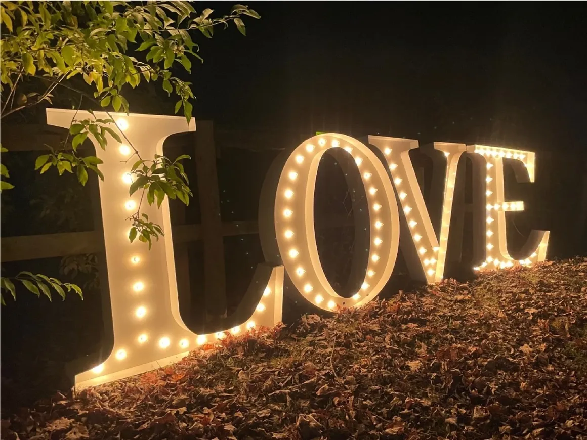 rs=w_1160,h_870 Large illuminated marquee letters spelling "LOVE" placed outdoors on fallen leaves at night, highlighting the romantic and elegant atmosphere